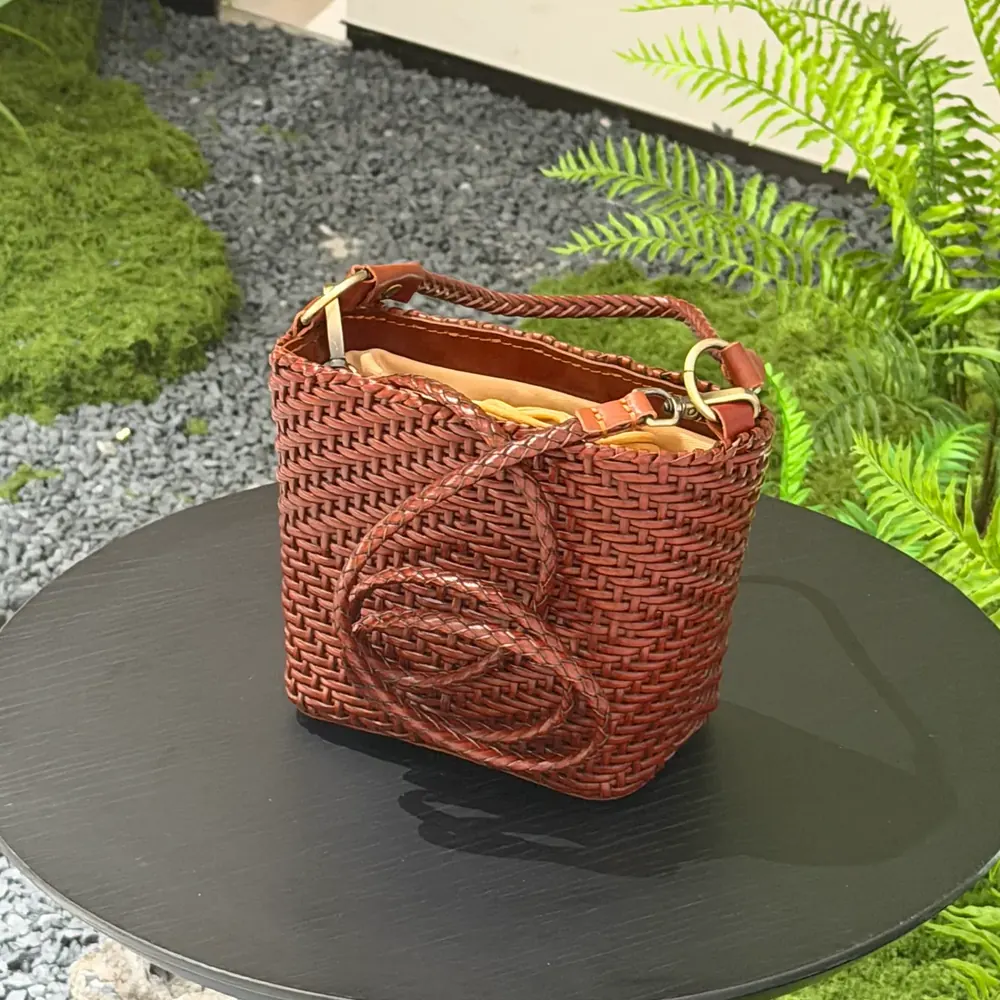 TG-90105 small brown square woven leather handbag on a round table, viewed from slightly above with the handle and open top visible