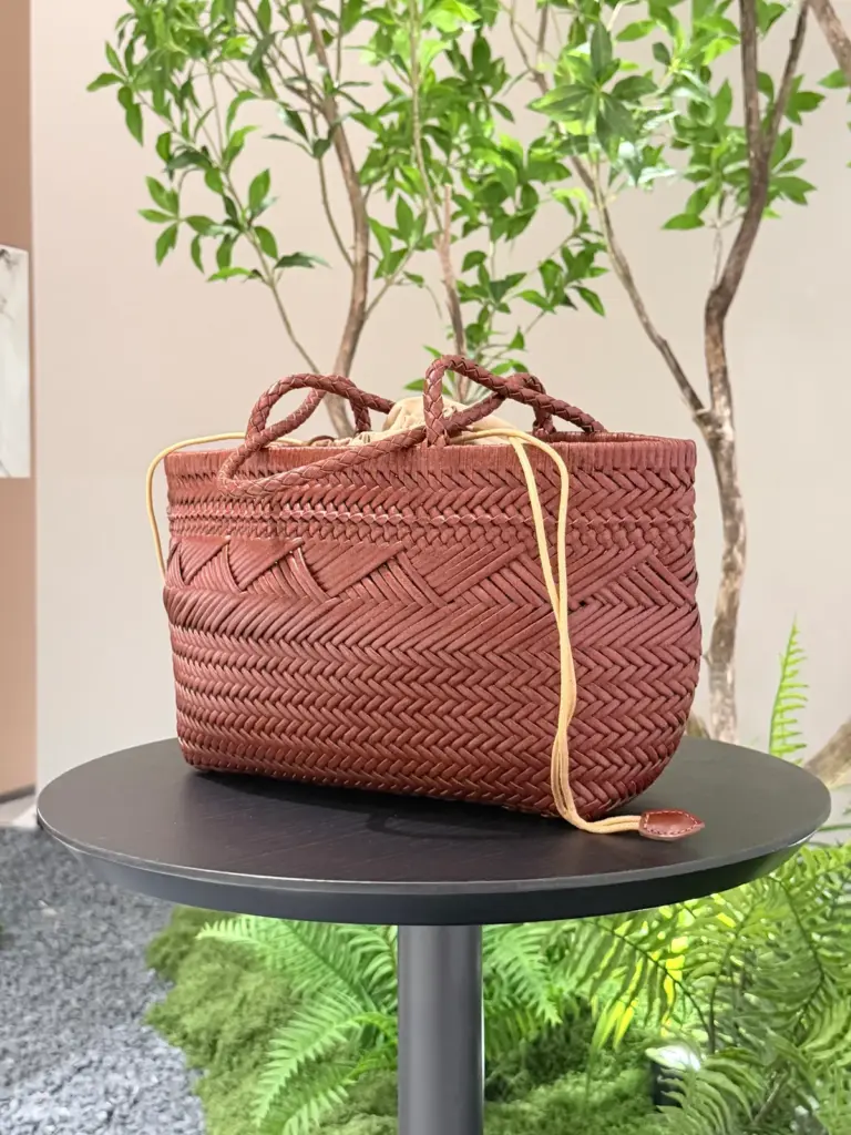 Mixed weave leather tote in Reddish brown (shown), with two short handles and a separate fabric inner bag on a round table