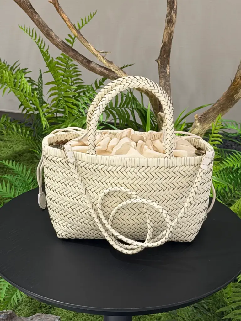 Cream woven leather handbag with two handles, a detachable shoulder strap and a separate fabric inner bag